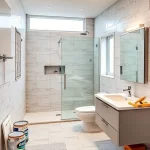A modern bathroom undergoing a full renovation, with partially installed tiles, a new shower enclosure, a sleek vanity with a sink, a toilet, a floor-to-ceiling window, and construction materials like paint cans, a tile cutter, and a toolbox visible in the background. The scene shows a clean, organized workspace with a focus on the transformation process, highlighting the contrast between the old and new elements.