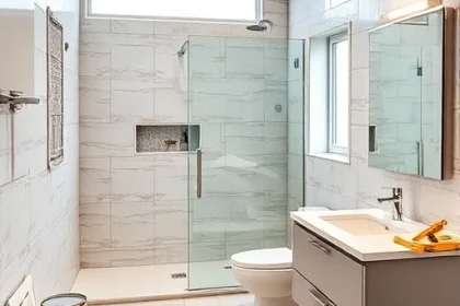 A modern bathroom undergoing a full renovation, with partially installed tiles, a new shower enclosure, a sleek vanity with a sink, a toilet, a floor-to-ceiling window, and construction materials like paint cans, a tile cutter, and a toolbox visible in the background. The scene shows a clean, organized workspace with a focus on the transformation process, highlighting the contrast between the old and new elements.