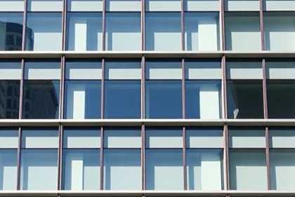 A modern building facade featuring sleek thermopane windows arranged in a grid pattern, showing clear glass panels with metallic frames, reflecting sunlight, with a clean architectural design and minimalist aesthetic, smallHQ