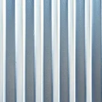 A close-up of a galvanized steel sheet used for a fence, showing its textured zinc coating with a subtle crystalline pattern, placed vertically as part of a modern outdoor fence under natural daylight, with soft shadows and no background distractions